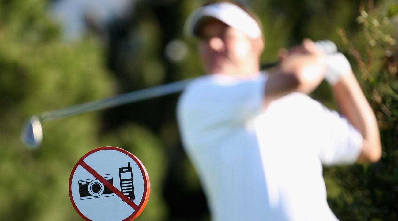 Golfer in backswing with "no phones or cameras" sign in background