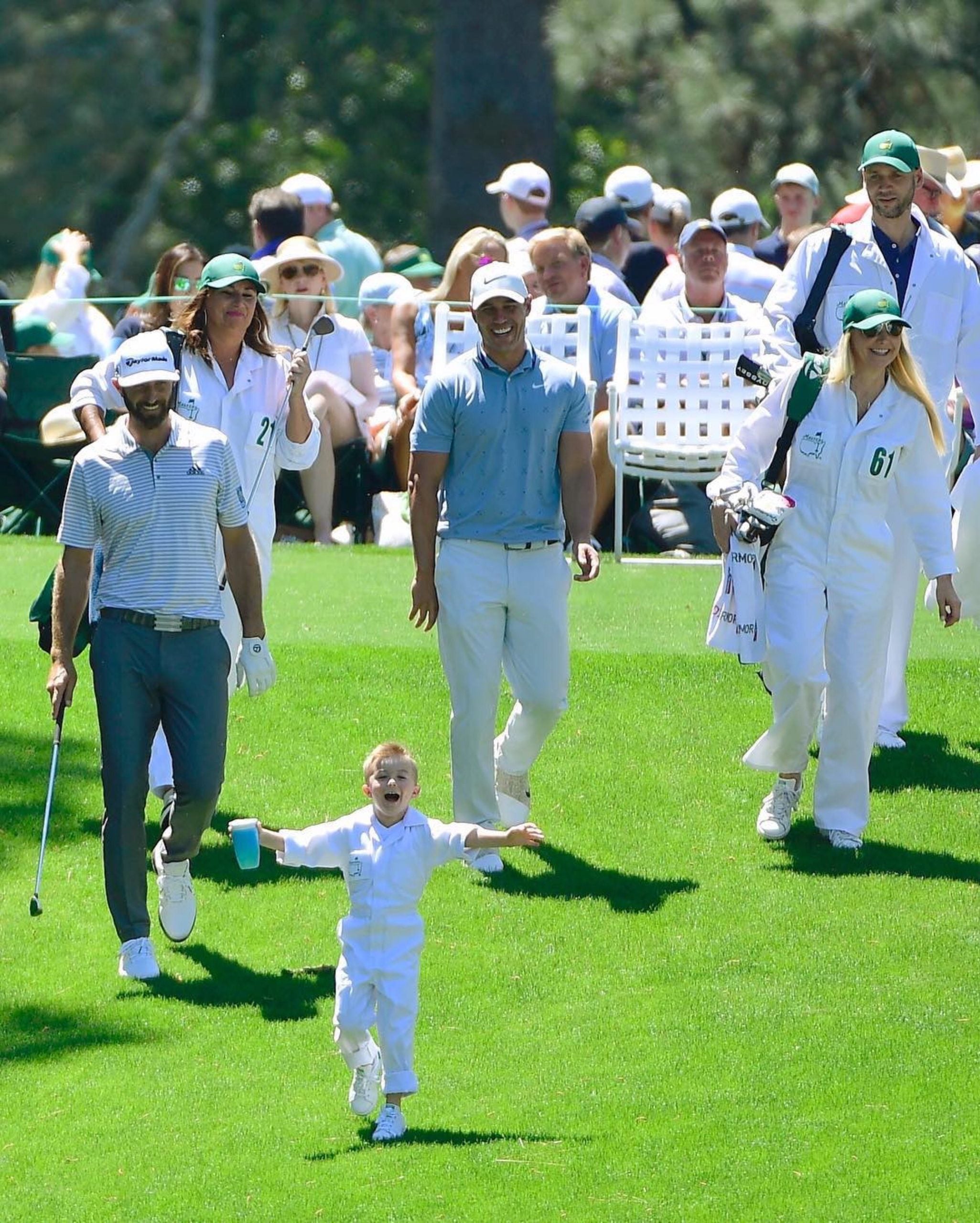 Dustin Johnson and Brooks Koepka come down the fairway together following a kid.