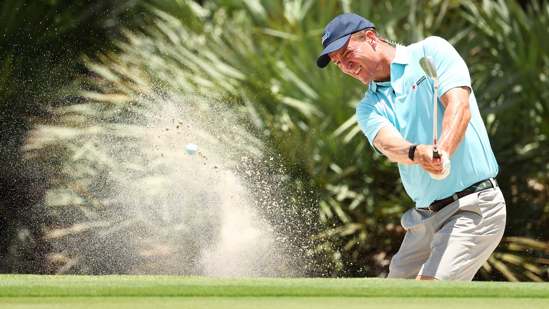 Peyton Manning hits out of a sand trap during a practice round on Saturday.