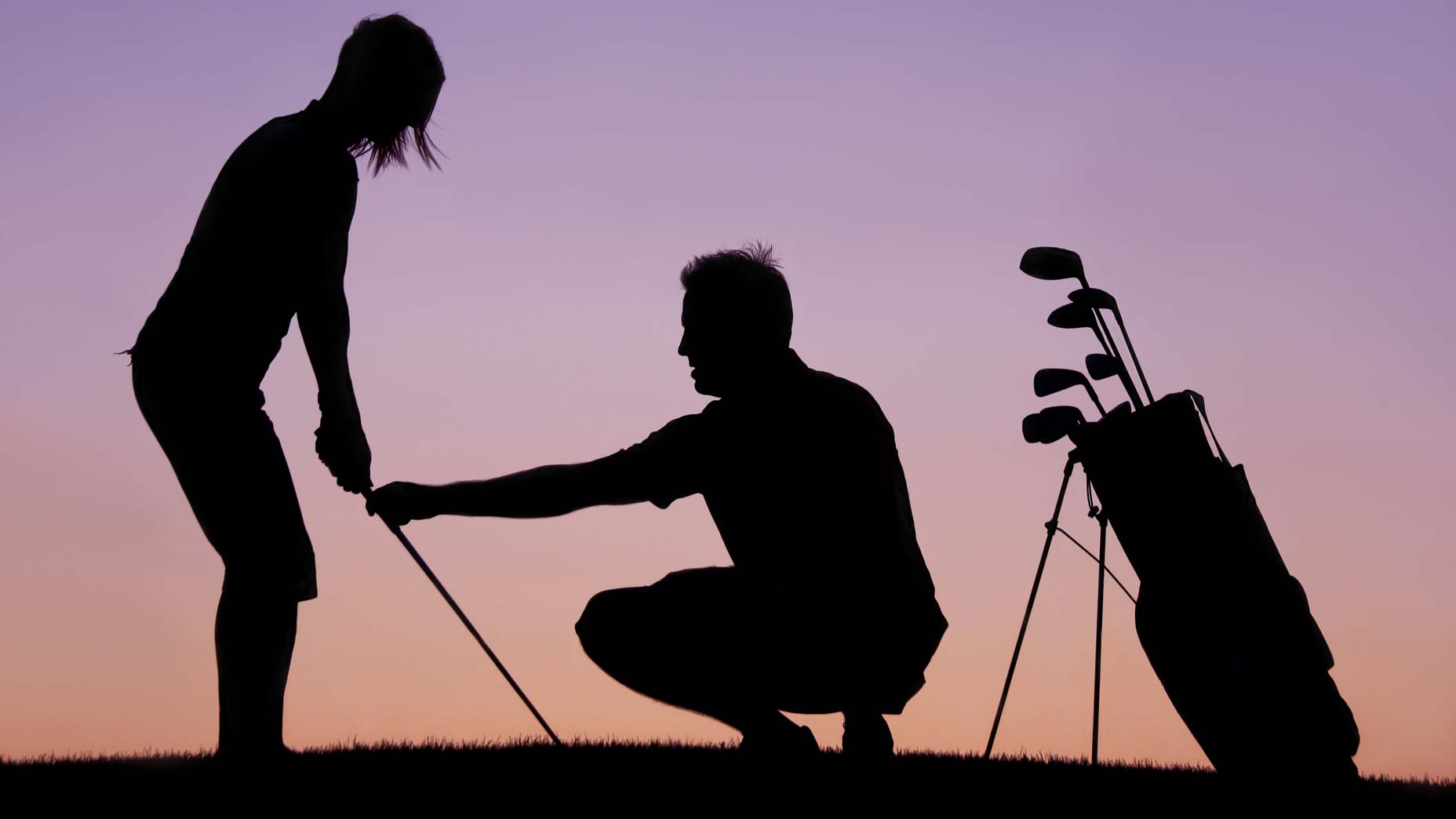 man gives golf swing lesson as sun sets