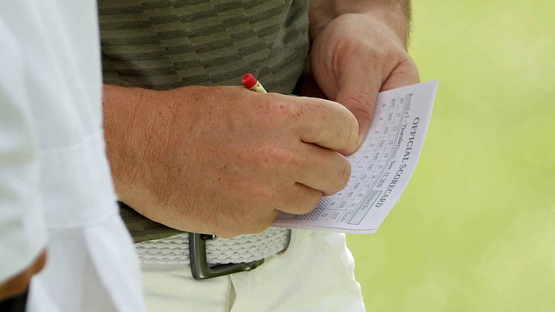 man writes on scorecard