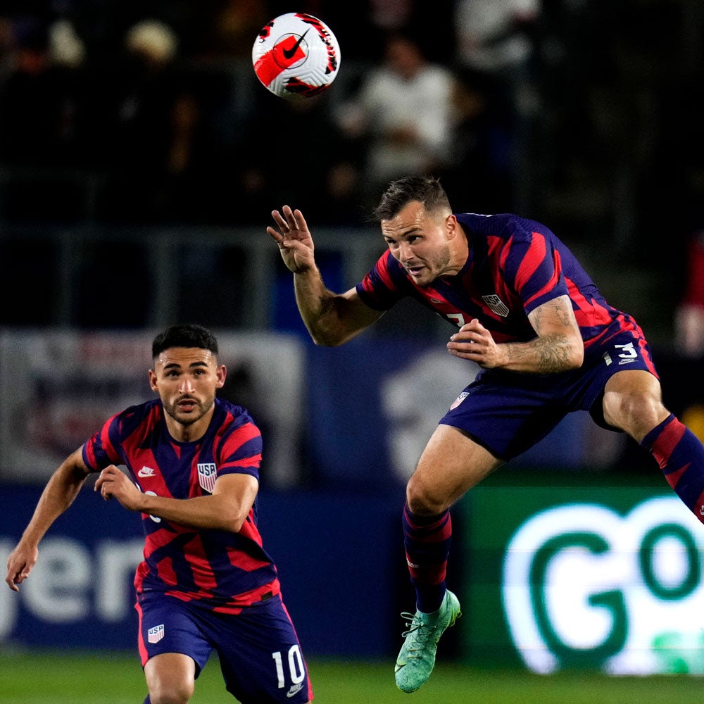 Jordan Morris gets a head on the ball playing for Team USA, with Cristian Roldan looking on.