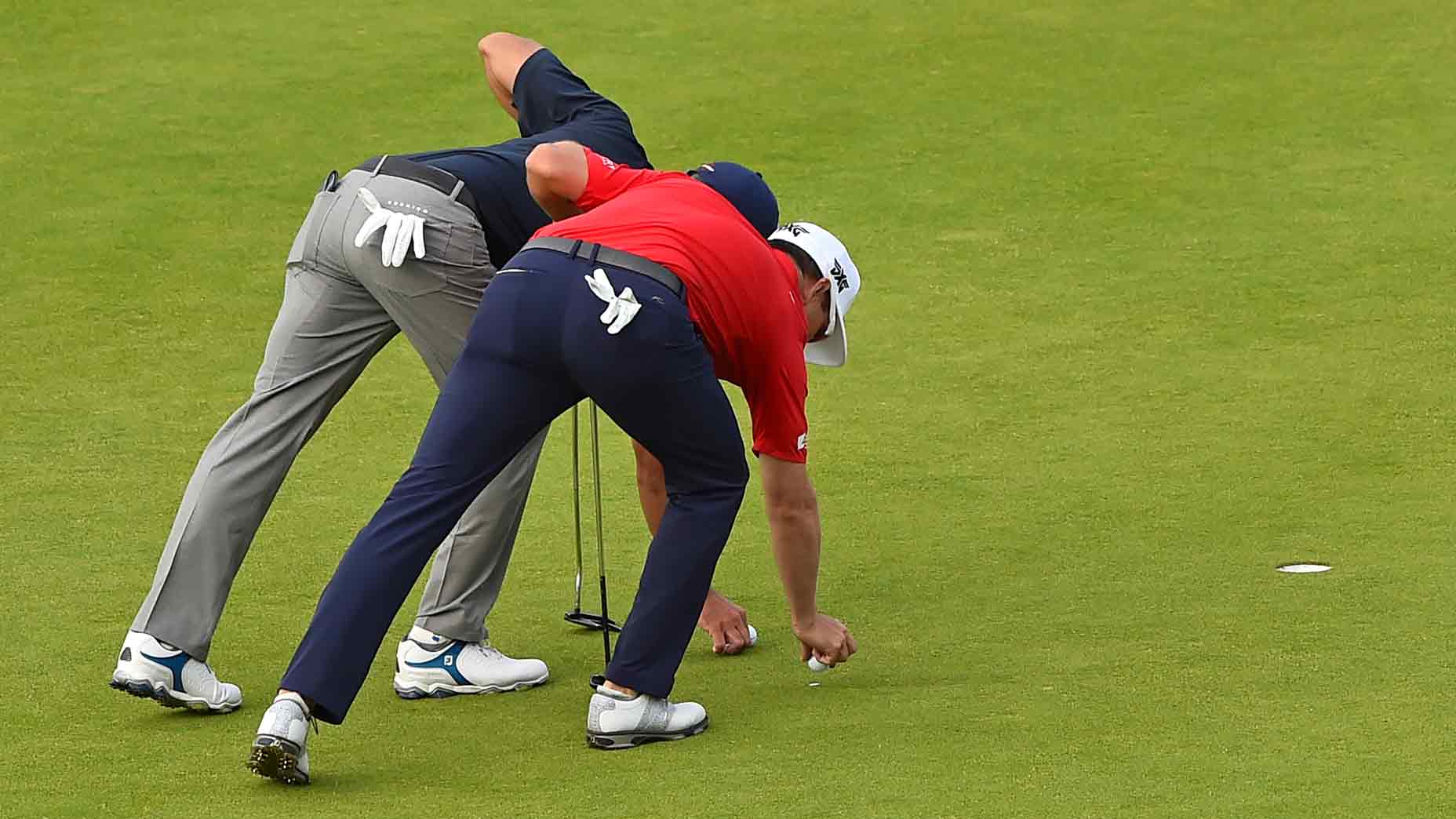 Golfers marking balls on green