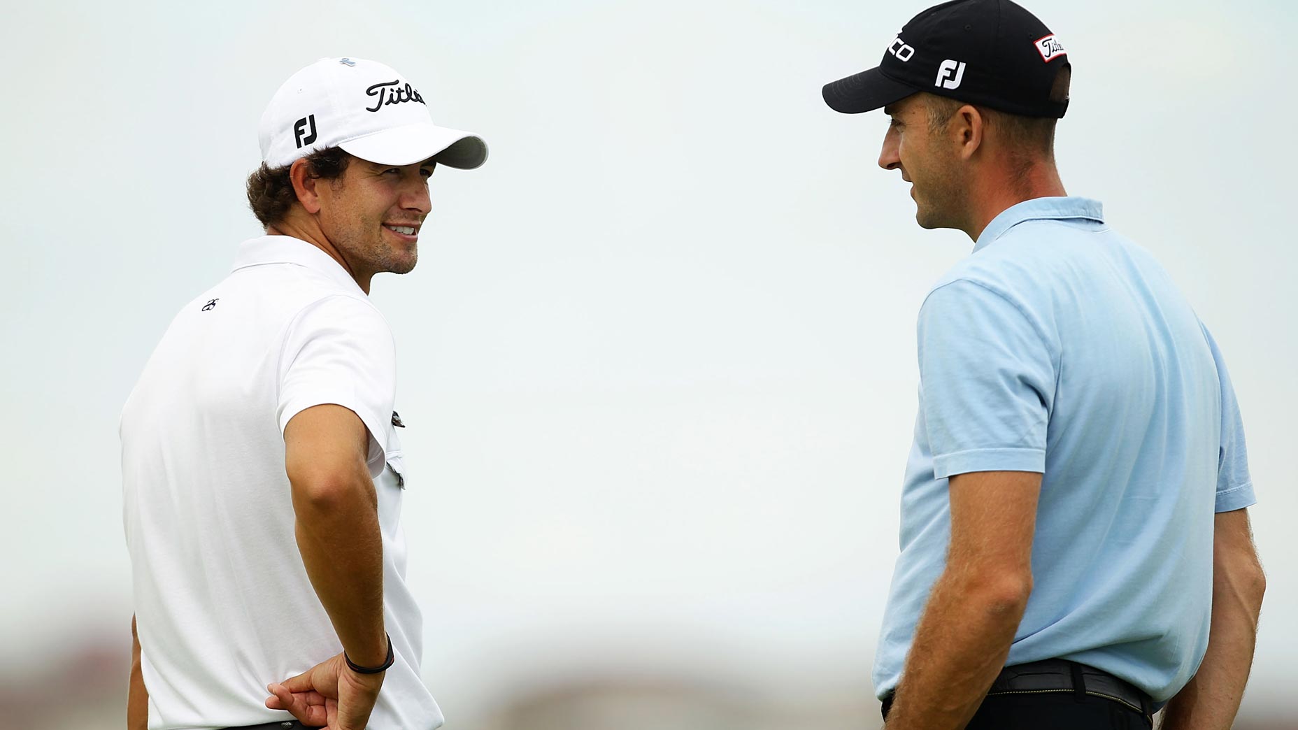 Adam Scott of Australia speaks to Geoff Ogilvy of Australia during day one of the Australian Open at The Lakes Golf Club on December 2, 2010 in Sydney, Australia.