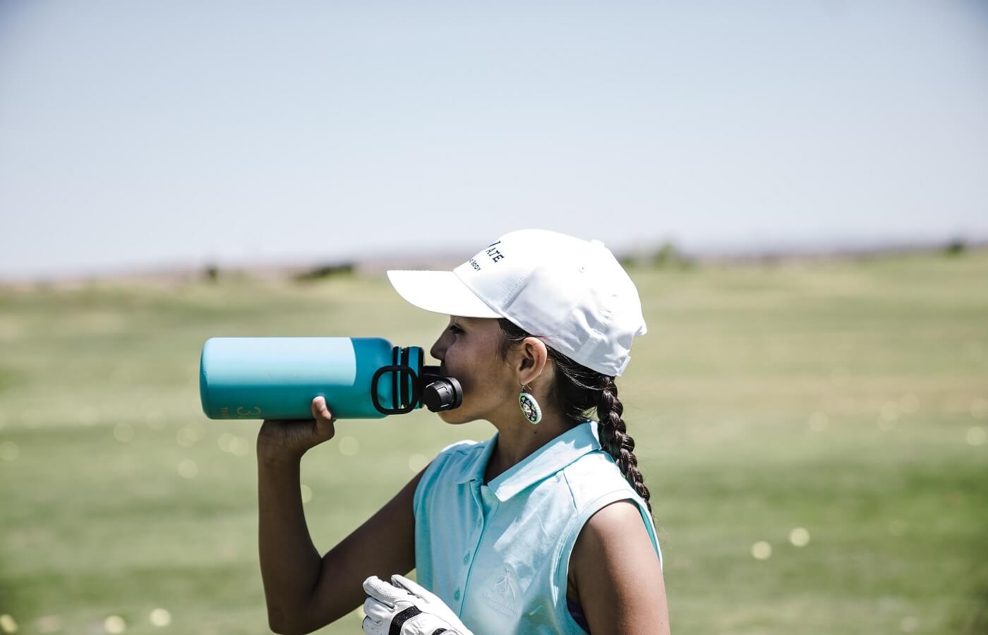 Woman golfer drinking from a water bottle