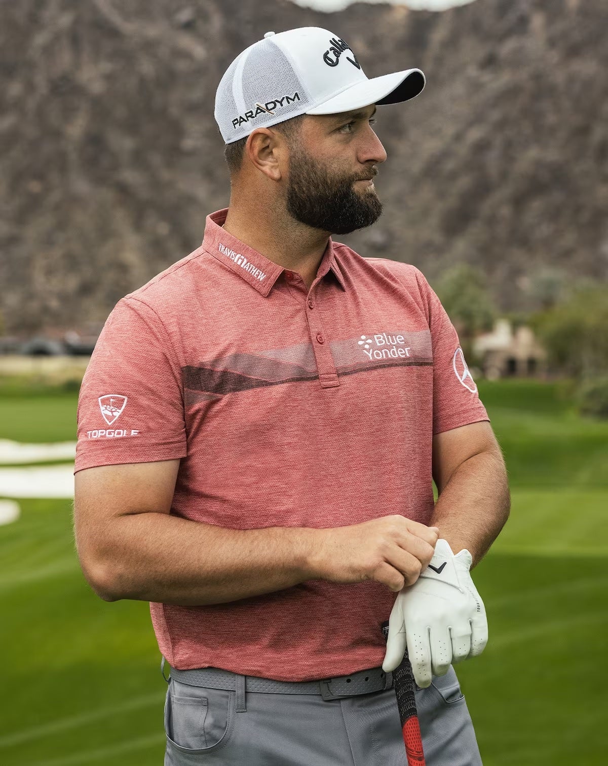 Jon Rahm wearing a red Travis Mathew Grand Heater golf polo.