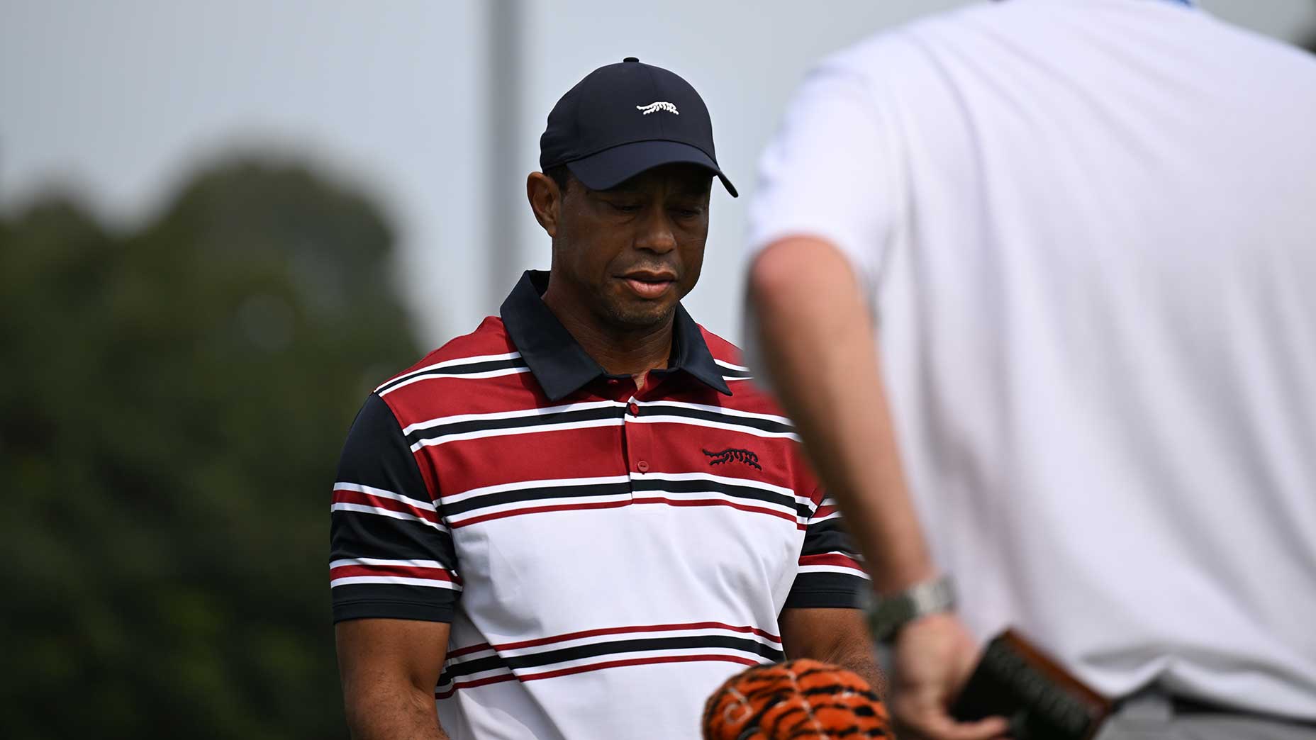 tiger woods grimaces at genesis invitational in red striped shirt