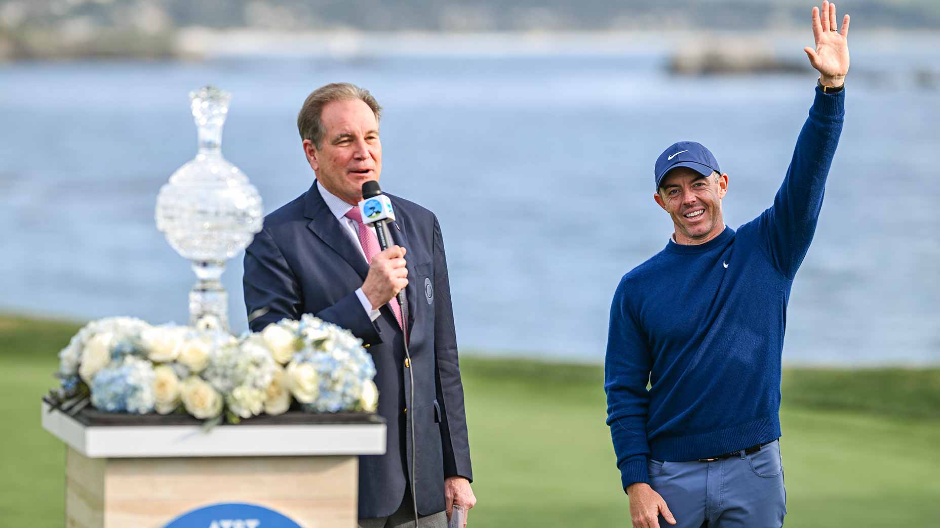 jim nantz speaks into microphone at AT&T Pebble Beach Pro-Am next to Rory McIlroy.
