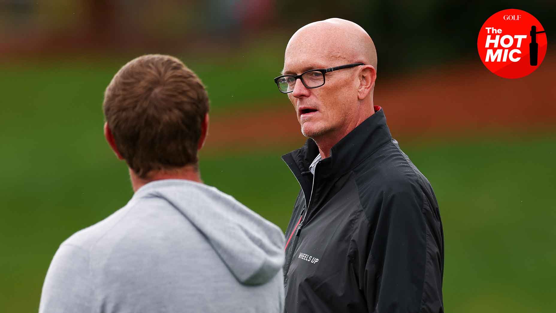 scott van pelt talks to person at the PGA Championship in black rain jacket