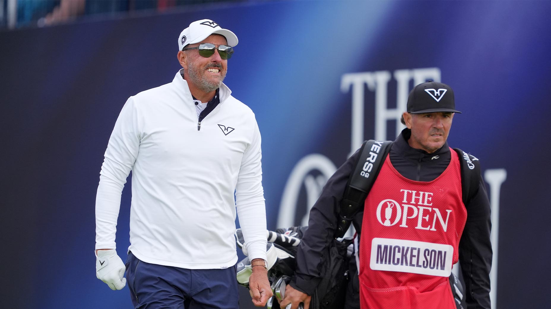 phil mickelson smiles next to caddie in white shirt and white hat at the open championship