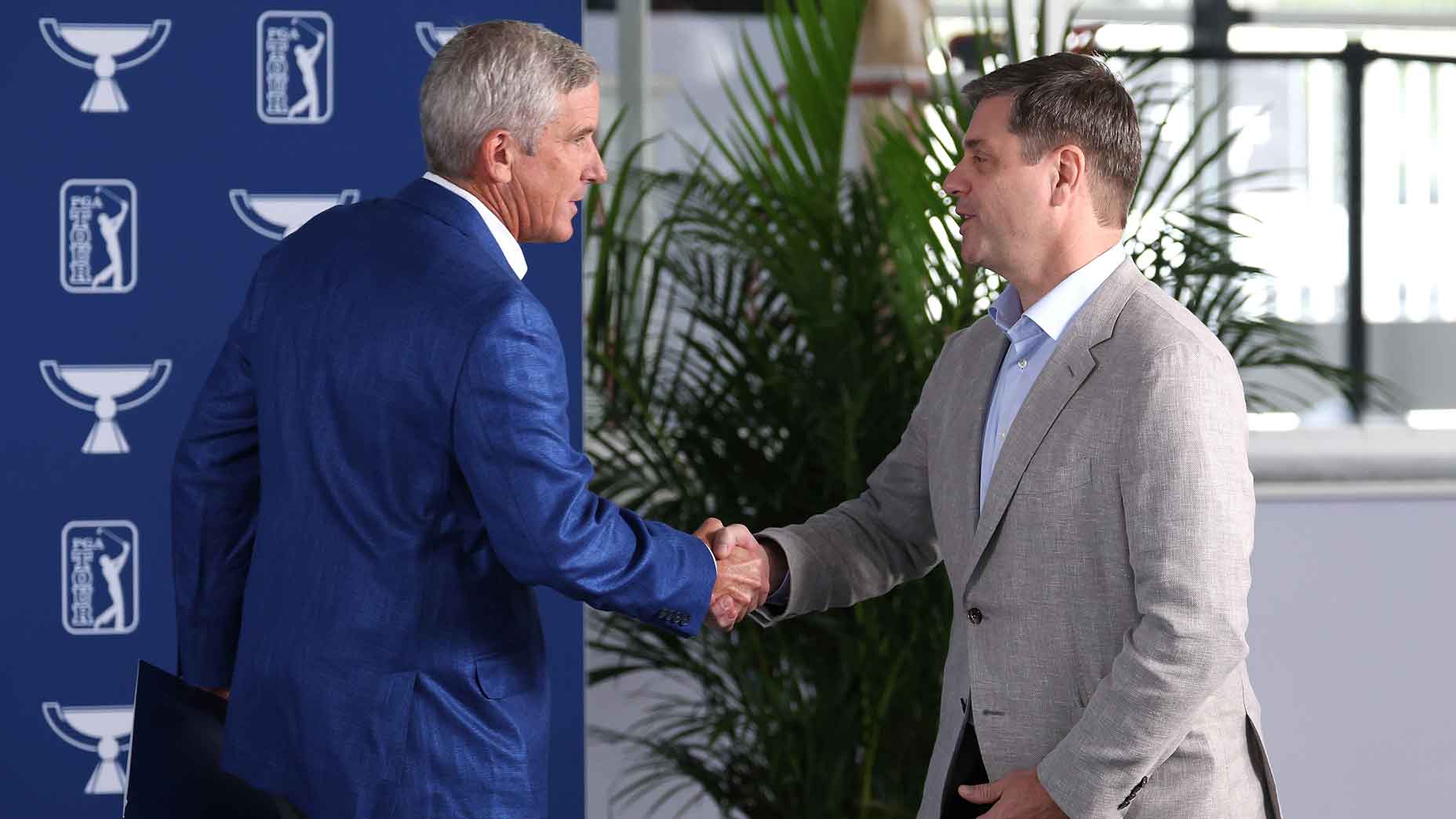 Outgoing PGA Tour commissioner Jay Monahan shaking hands with new CEO Brian Rolapp.