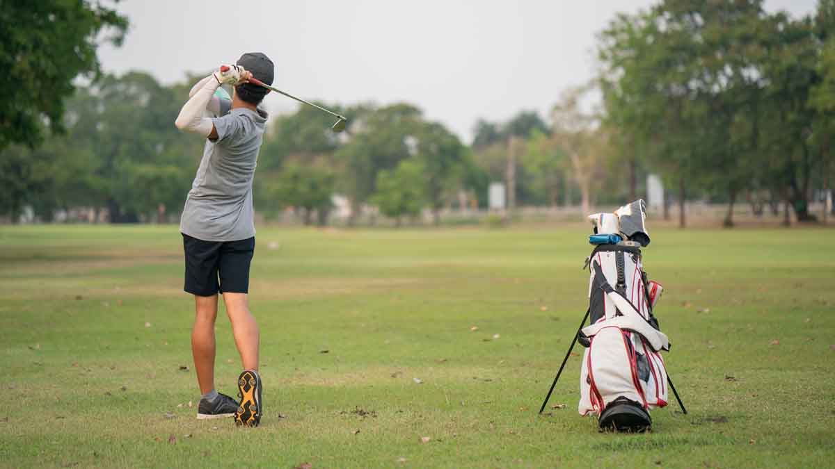 Boy golf player hitting by iron from fairway