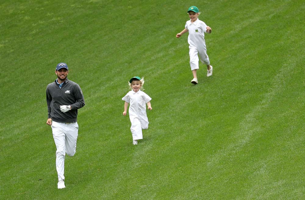 <p/>Wesley Bryan runs down a hill during the Masters Par 3 Contest with two young caddies in tow.